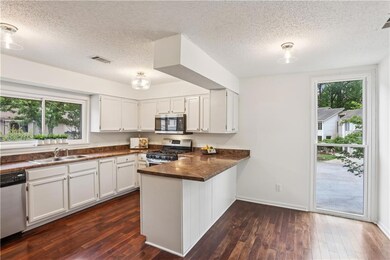 Kitchen featuring stainless steel appliances, a sink, dark countertops, a peninsula, and a textured ceiling