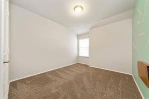 Spare room featuring dark carpet and baseboards