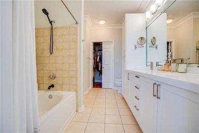 Bathroom featuring crown molding, shower / bath combo, vanity, light tile patterned floors, and a walk in closet