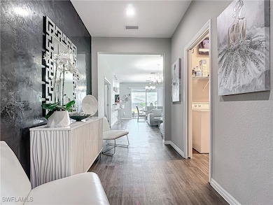 Hallway with a notable chandelier, visible vents,