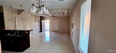 Kitchen with light tile patterned floors, ceiling fan with notable chandelier, a sink, dark countertops, and visible vents