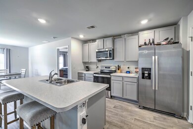 Kitchen featuring gray cabinetry, light wood-style flooring, a sink, appliances with stainless steel finishes, and light countertops