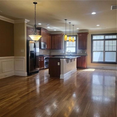 Kitchen with fridge, crown molding, a breakfast bar area, dark wood finished floors, and a kitchen island