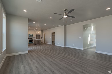Unfurnished living room featuring recessed lighting, dark wood-style flooring, a textured ceiling, and ceiling fan