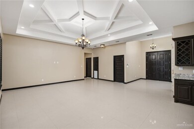Unfurnished living room with light tile floors, a notable chandelier, coffered ceiling, and beamed ceiling