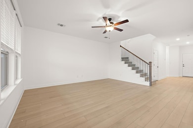 Unfurnished living room with stairs, ceiling fan,