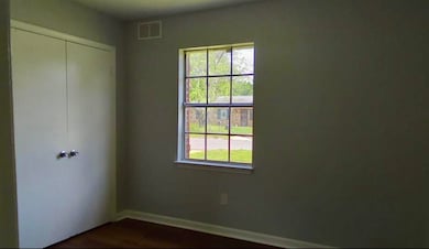 Unfurnished bedroom featuring baseboards, a closet, and dark wood-style flooring