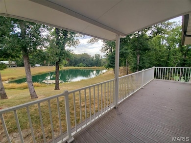Wooden deck with a water view, a lawn, and view of scattered trees