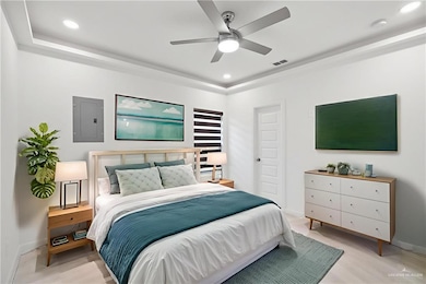 Bedroom featuring electric panel, a tray ceiling, recessed lighting, a ceiling fan, and light wood-style flooring