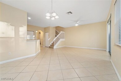 Empty room featuring light tile patterned floors, ceiling fan, stairway, a chandelier, and arched walkways
