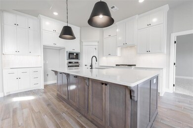 Kitchen featuring decorative backsplash, white cabinetry, an island with sink, dark brown cabinetry, and recessed lighting