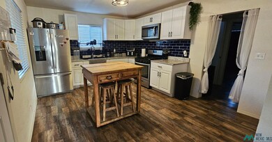 Kitchen with appliances with stainless steel finishes, white cabinetry, tasteful backsplash, and dark wood-style floors
