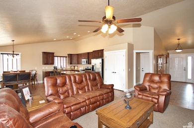 Living room with a ceiling fan, a chandelier, a textured ceiling, high vaulted ceiling, and recessed lighting