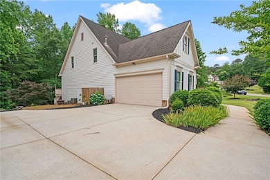 View of side of home featuring concrete driveway, a garage, a shingled roof, board and batten siding, and central AC unit