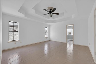 Spare room with light tile patterned floors, baseboards, a raised ceiling, and a ceiling fan