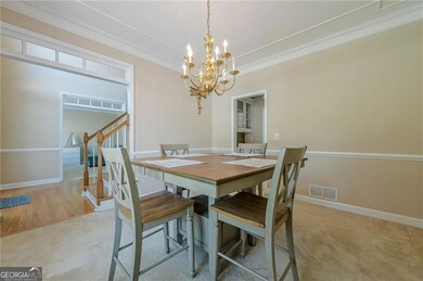 Dining space with a chandelier, crown molding, light colored carpet, baseboards, and stairway
