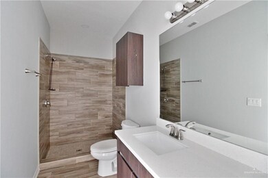 Bathroom featuring vanity, a tile shower, and toilet