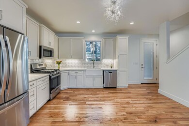 Kitchen featuring appliances with stainless steel finishes, white cabinetry, decorative backsplash, recessed lighting, and light wood-type flooring