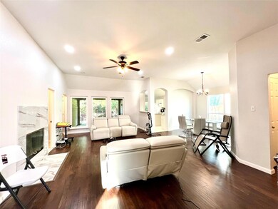 Living room with a high end fireplace, ceiling fan with notable chandelier, dark hardwood / wood-style floors, and vaulted ceiling