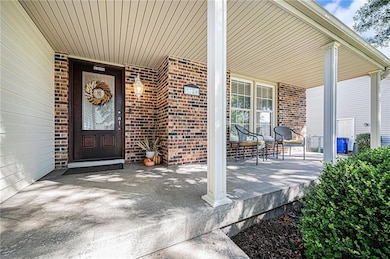 View of exterior entry featuring covered porch and brick siding