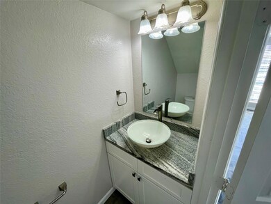 Half bath featuring a textured wall and vanity