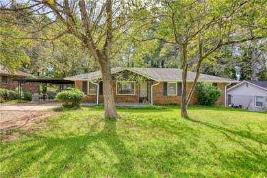 Ranch-style home featuring a front yard, a carport, brick siding, and driveway