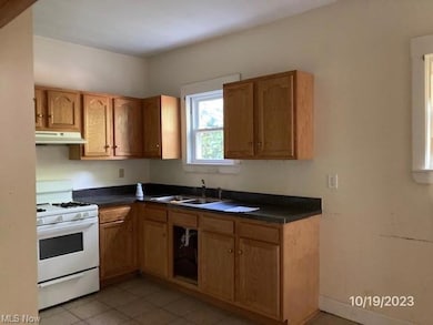 Kitchen featuring sink, white gas range oven, and light tile floors