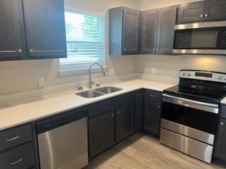 Kitchen with appliances with stainless steel finishes, light wood-type flooring, and light countertops