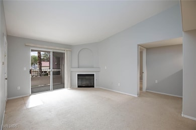 Unfurnished living room featuring a glass covered fireplace and light carpet