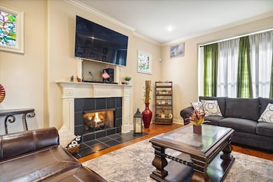 Living room with a tile fireplace, dark wood-type flooring, crown molding, and a healthy amount of sunlight