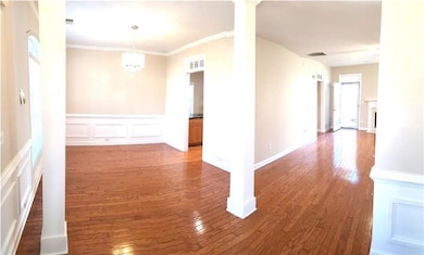 Spare room with a decorative wall, wainscoting, wood-type flooring, crown molding, and a chandelier