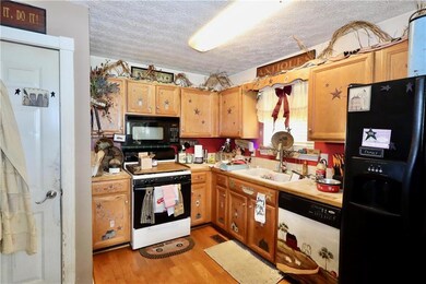 Kitchen featuring light countertops, a textured ceiling, black appliances, and light wood-type flooring