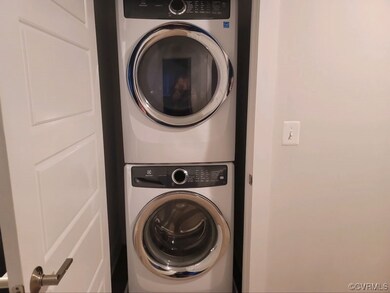 Clothes washing area featuring stacked washer and clothes dryer