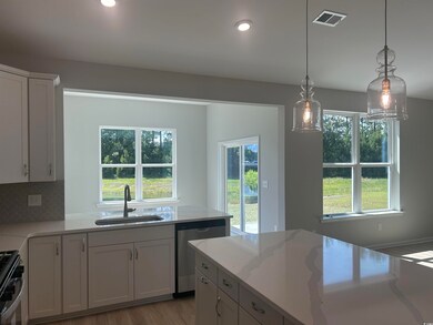 Kitchen with appliances with stainless steel finishes, a sink, white cabinets, light stone counters, and pendant lighting