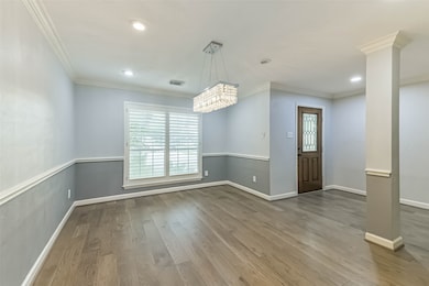 Elegant dining room featuring sleek hardwood floors, a stunning chandelier, and abundant natural light. Perfect for entertaining.