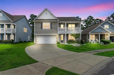 View of front facade with board and batten siding, concrete driveway, a garage, a lawn, and a balcony