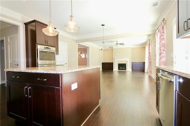 Kitchen featuring decorative light fixtures, ornamental molding, hardwood / wood-style floors, and stainless steel dishwasher