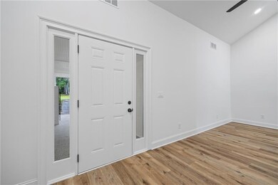 Foyer entrance with vaulted ceiling, wood finished floors, baseboards, and a ceiling fan