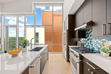 This stylish kitchen features an oversized center island with waterfall edge, quartz countertops, Jenn-Air stainless steel appliances.