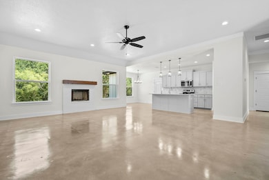 Unfurnished living room with recessed lighting, a chandelier, finished concrete flooring, a ceiling fan, and a fireplace