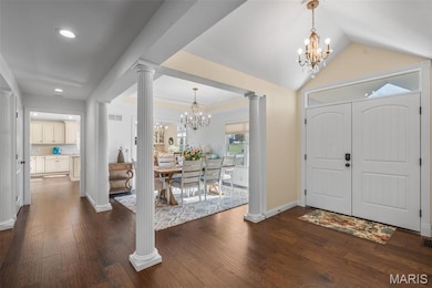 Entrance foyer featuring a chandelier, wood finished floors, decorative columns, lofted ceiling, and recessed lighting