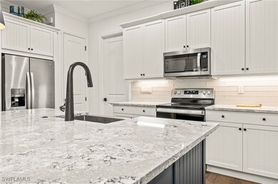 Kitchen featuring white cabinetry, light stone cou