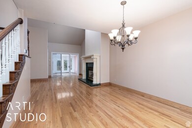 Unfurnished living room featuring light wood-type flooring, stairway, a chandelier, and a premium fireplace