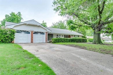 Single story home featuring brick siding, a garage, concrete driveway, and a front yard