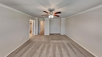 Carpeted empty room featuring ornamental molding and ceiling fan