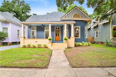 View of front of property featuring a porch, a front lawn, a shingled roof, and a ceiling fan