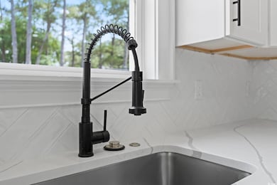 Kitchen view of backsplash, a sink, white cabinets