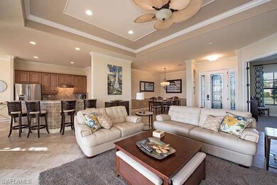 Living area featuring a raised ceiling, recessed lighting, crown molding, light tile patterned floors, and a ceiling fan