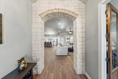 Hall featuring arched walkways, wood finished floors, and a textured wall