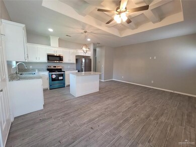 Kitchen with appliances with stainless steel finishes, a raised ceiling, a sink, wood finished floors, and a kitchen island